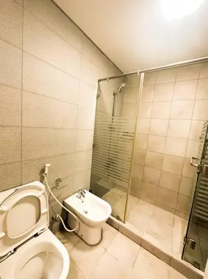 a bathroom with a toilet and a glass shower at central apartment for rent 24 in Umm Uthainah