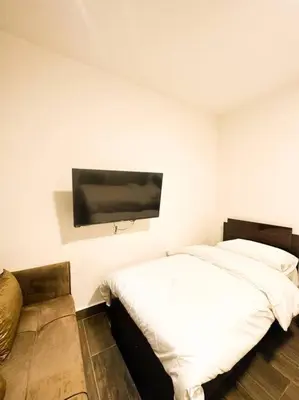 a bedroom with a bed and a flat screen tv on the wall at central apartment for rent 24 in Umm Uthainah