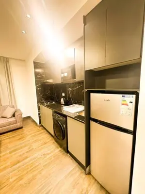 a small kitchen with a refrigerator and a stove at central apartment for rent 25 in Umm Uthainah