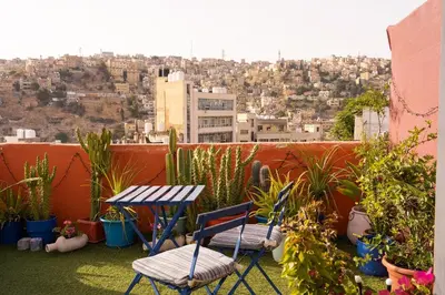two chairs and a table on a balcony with plants at Medusa Home Stay in Amman