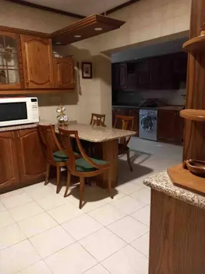 a kitchen with a table and chairs and a microwave at Charming Apartment in Shmeisani in Amman