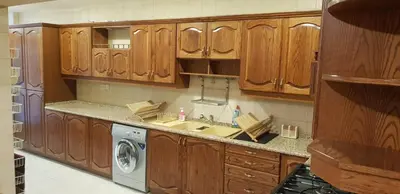 a kitchen with wooden cabinets and a washing machine at Charming Apartment in Shmeisani in Amman