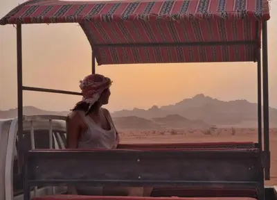 a woman sitting on a vehicle in the desert at Wadi rum Rozana camp in Wadi Rum