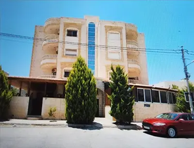 a red car parked in front of a building at Shafa Badran Families Apt in Amman