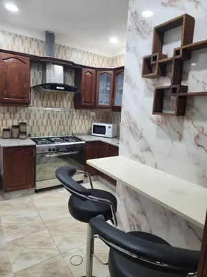 a kitchen with a counter and two chairs in it at Shafa Badran Families Apt in Amman