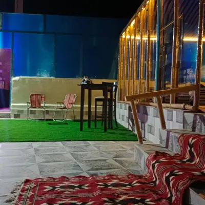 a table and a chair in a room with a rug at shalyh tal birin in Şarrūt