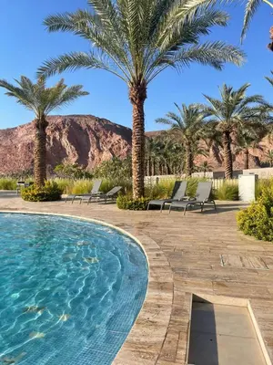 a swimming pool in a resort with palm trees at Alraha VIP Marsa zayed Aqaba in Aqaba