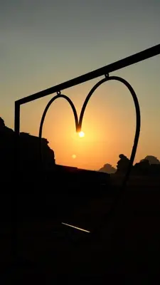 a heart shaped sign with the sunset in the background at Rum Under The Stars Camp in Wadi Rum