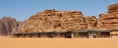 a building in the desert next to a mountain at Rum Under The Stars Camp in Wadi Rum