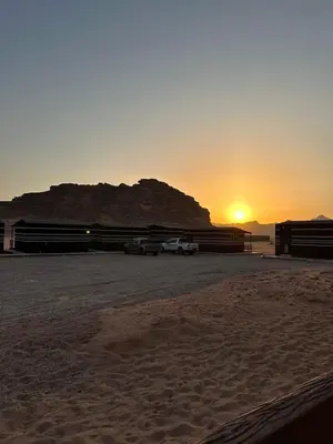 two cars parked in a parking lot with the sunset in the background at Rum Under The Stars Camp in Wadi Rum