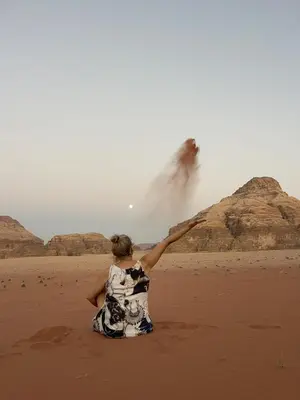 a woman sitting on the beach pointing at a wave at Rum Under The Stars Camp in Wadi Rum