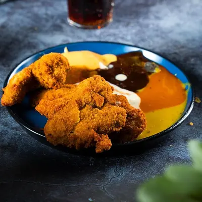 a blue plate of food with fried chicken and sauce at Al Joude Hotel فندق الجود in Irbid