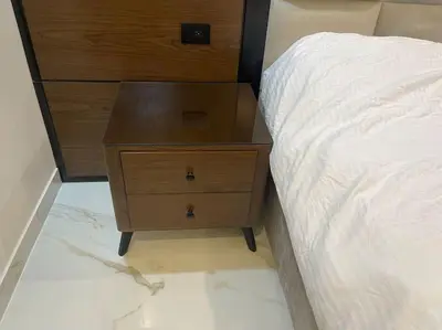 a wooden dresser next to a bed and a drawer at Oqdeh Delux Apartments in Jerash
