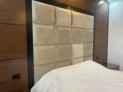 a bedroom with a white bed and a wooden wall at Oqdeh Delux Apartments in Jerash