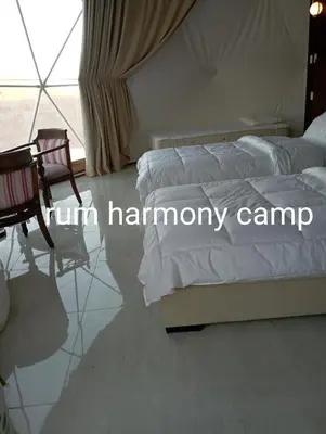 a bedroom with two beds and a chair and a window at Armony rum camp in Wadi Rum