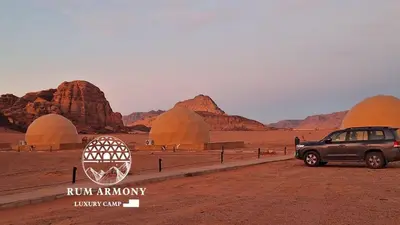 a suv parked in front of domes in the desert at Armony rum camp in Wadi Rum