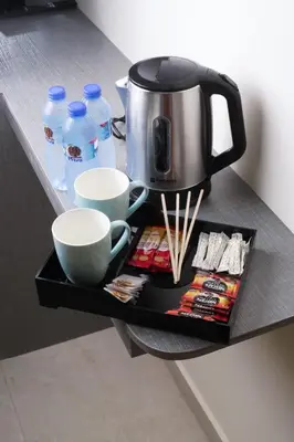 a tray with a coffee pot and cups on a counter at Three Palms Suites in Aqaba