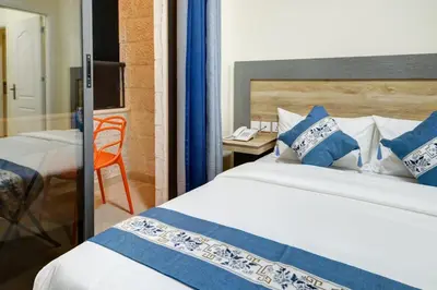 a bedroom with a bed with blue and white pillows at Three Palms Suites in Aqaba