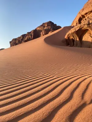 a sand dune in the desert with rocks in the background at Desert's Soul Wadi Rum in Disah
