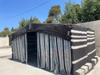 a black shelter with curtains on the side of a building at The Pine Tree Chalet in Jerash
