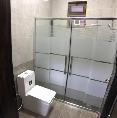 a bathroom with a toilet and a glass shower at The Pine Tree Chalet in Jerash