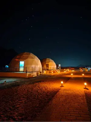 two domes at night with lights on the ground at Sami Al Muzna Rum Camp in Wadi Rum
