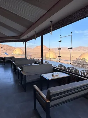 a restaurant with benches and tables and a view of the desert at Mirage Camp Wadi Rum in Wadi Rum