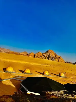 a group of tents in a desert with mountains in the background at Mirage Camp Wadi Rum in Wadi Rum