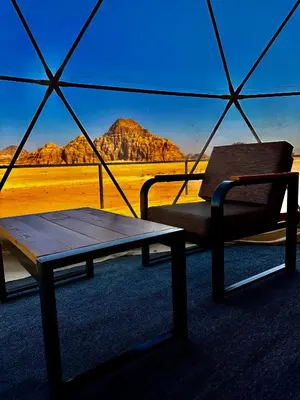 a tent with a table and a bench in the desert at Mirage Camp Wadi Rum in Wadi Rum