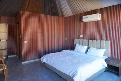 a bedroom with a bed with a red wall at Mirage Camp Wadi Rum in Wadi Rum