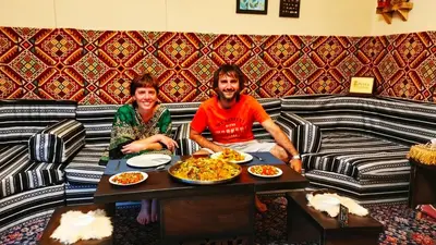 a man and a woman sitting at a table with food at Grandma's house in Wadi Musa