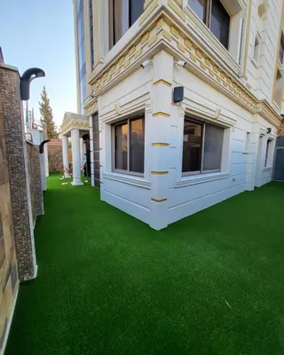 a yard with green grass next to a building at Pretal Hotel in Al Mafraq