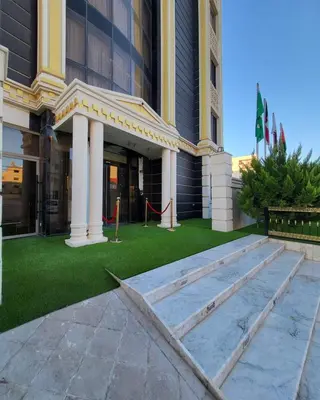 a building with a green lawn in front of it at Pretal Hotel in Al Mafraq