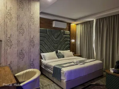 a bedroom with a large bed and a chair at Pretal Hotel in Al Mafraq