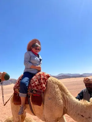 a woman riding a camel in the desert at Wadi Rum Spring Moon & Jeep Tour in Wadi Rum