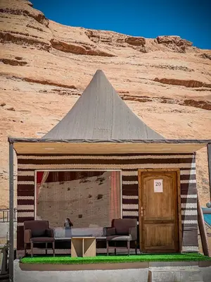 a building with two chairs and a pyramid at Sun Luxury Rum Camp in Wadi Rum
