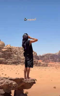 a man standing on a rock in the desert with a kite at Talal Wadi Rum in Wadi Rum