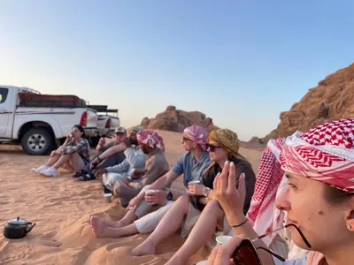 a group of people sitting in the sand in the desert at Talal Wadi Rum in Wadi Rum