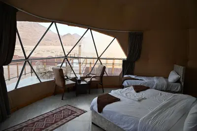 a room with two beds and a large window at Bilal luxury camp in Wadi Rum