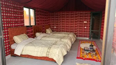 a bedroom with two beds in a room with red walls at Bedouin Nature Camp in Wadi Rum
