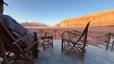 a person sitting in a chair on a patio looking at the desert at Bedouin Nature Camp in Wadi Rum