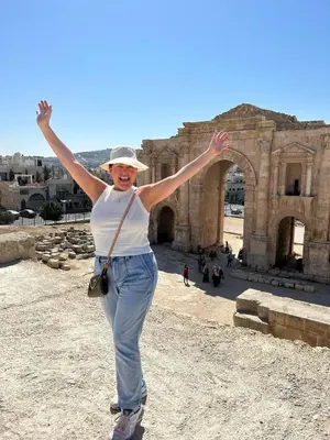 a woman standing in front of a building with her arms up at بيت جرش - Jerash House in Jerash