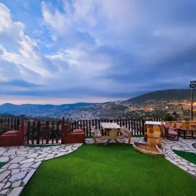 a patio with green grass and a view of a city at Mount lareen cottage كوخ جبل لارين in Ajloun