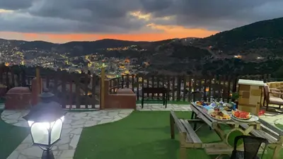 a person sitting on a patio with a table with food at Mount lareen cottage كوخ جبل لارين in Ajloun