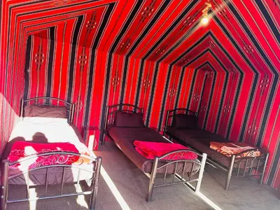 two beds in a room with red and black stripes at Milk way desert in Wadi Rum