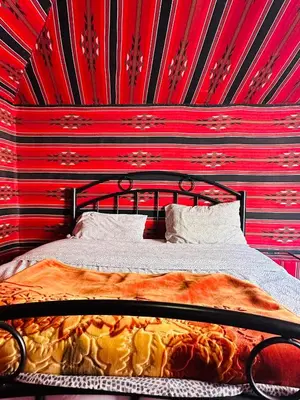 a bed in a room with a red wall at Milk way desert in Wadi Rum