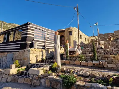a house with a stone wall and stairs in front of it at My Grandfathers House Dana Heritage and Eco Lodge in Dana