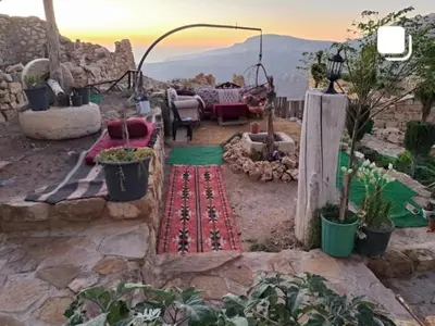 a garden with a table and chairs and a view of the mountains at My Grandfathers House Dana Heritage and Eco Lodge in Dana