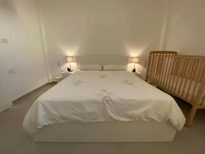 a bedroom with a white bed with two lamps at Qaimariya Farmhouse Amman - Day Use - Lodging - Events in Amman