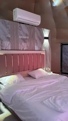 a bedroom with a large bed with white sheets and a light at Sidra Luxury Camp in Rum in Wadi Rum